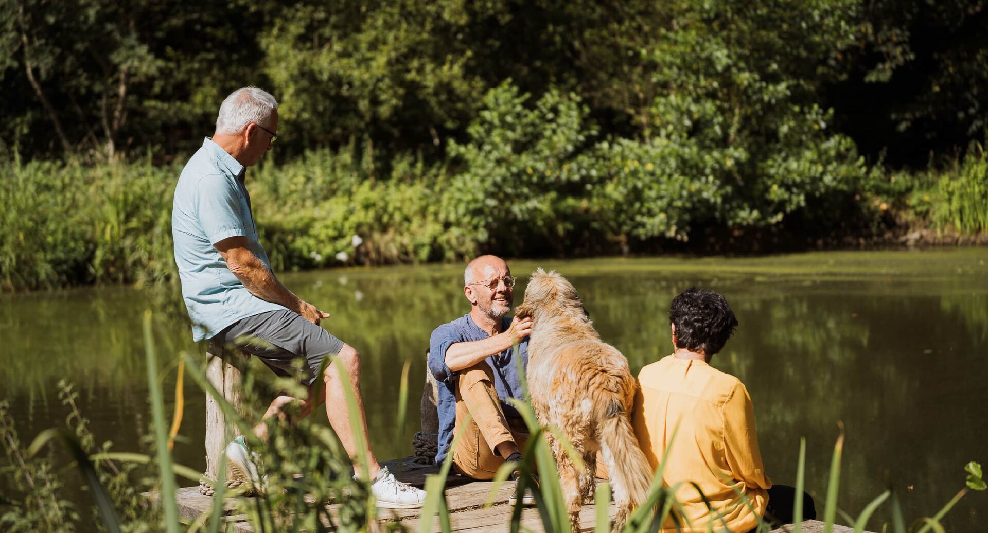Trois personnes et un chien au bord de l'étang